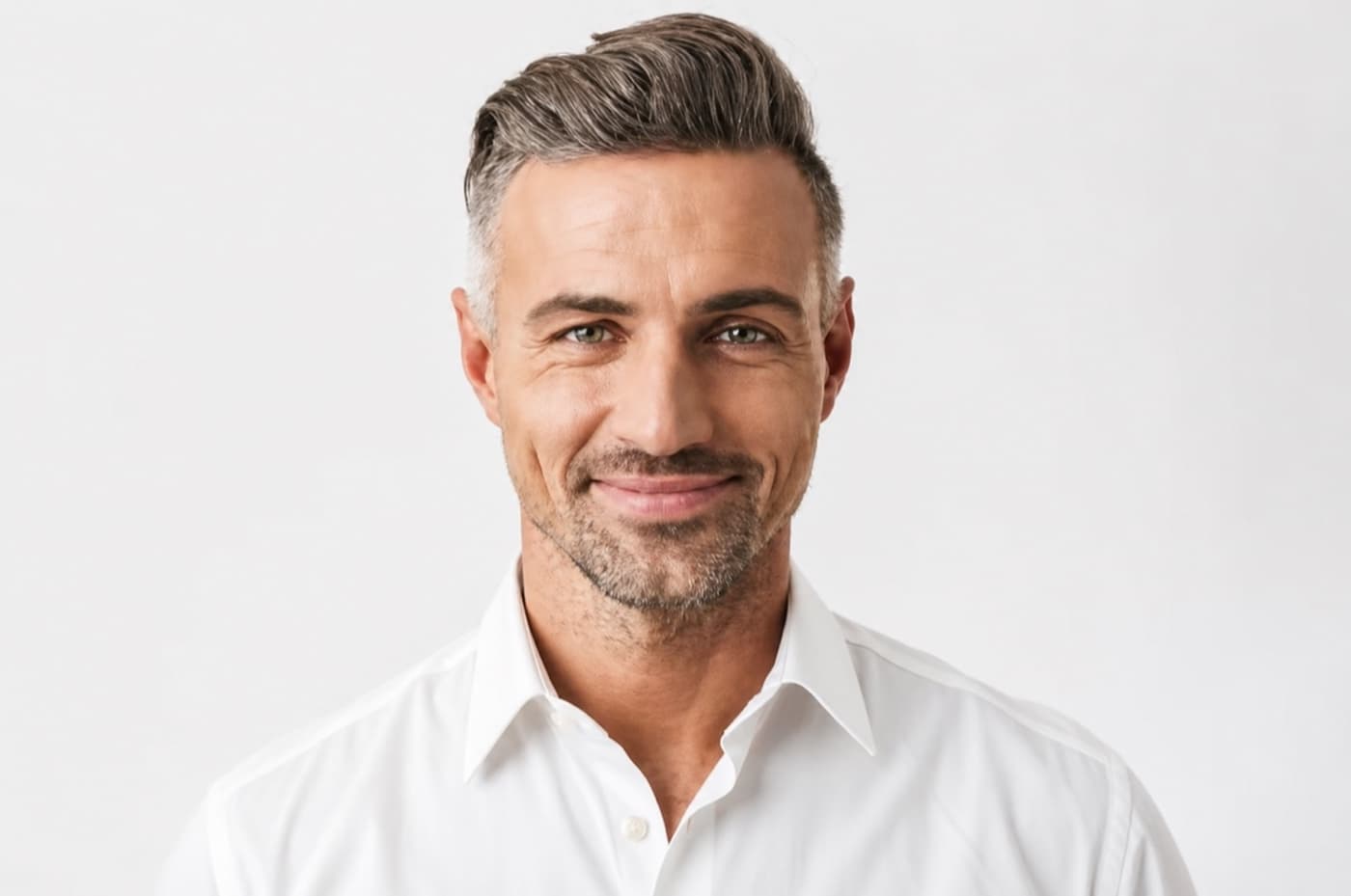 A man with silver hair in a white shirt, relaxed and self-assured.
